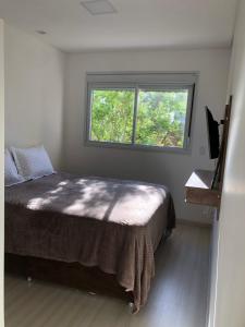 un dormitorio con una cama y una ventana en APARTAMENTO 205 , Canasvieiras, en Florianópolis