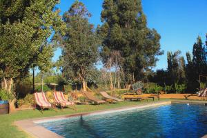 a swimming pool with two lawn chairs and a table at Hotel Boutique Raíces de Colchagua in Santa Cruz