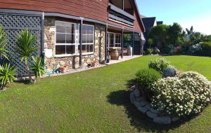 a house with a yard with flowers in front of it at Rarangi Seaview On the Beach B&B in Blenheim