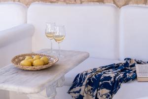 a table with two glasses of wine and a bowl of fruit at Happy Apartments Mykonos in Klouvas