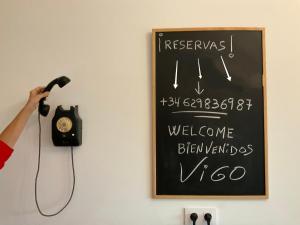 a person is holding a telephone and a sign on a wall at Casa nueva en Vigo con Jacuzzi y chimenea in Pontevedra