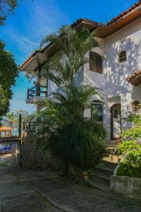 a palm tree in front of a white house at Casa da Cocanha COND com PISCINA-SINUCA-CHURRASQ-DECK com vista para o mar in Caraguatatuba