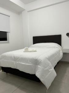 a white bed with a black headboard in a bedroom at Apart hotel Magda in Venado Tuerto