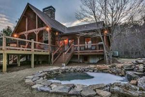 une maison en rondins avec un étang en face de celle-ci dans l'établissement Ruby River Lodge, à Ellijay