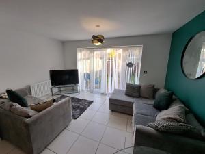 a living room with couches and a flat screen tv at 4BR Contractor Town House 2.5bathrooms, 2 free parking spaces managed by Chique Properties in Milton Keynes