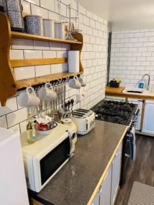 a kitchen with a stove and a microwave on a counter at Bikers Grove Cottage in Troed-y-rhiw