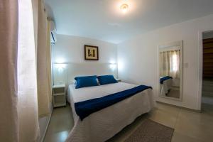 um quarto com uma cama com almofadas azuis e um espelho em Pousada Gravatá em Gravatal