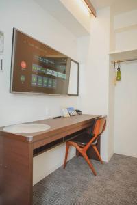 una scrivania con TV su un muro e sedia di Hotel Plaisir Akihabara a Tokyo