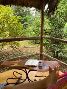 a person laying in a hammock with a table with books at Encantadora Villa Maya tradicional en Rancho Agroecologico in Tzucaceb