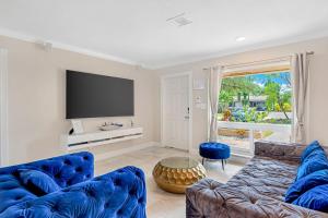 sala de estar con sofás azules y TV de pantalla plana en 3BDR Villa-HeatedPool-6minFt.Lauderdale Beach-8PPL, en Fort Lauderdale