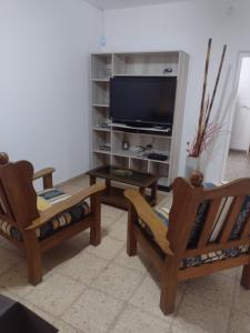 a living room with two chairs and a flat screen tv at Casa en Santa Rosa in Santa Rosa