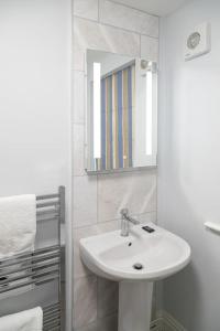 a white bathroom with a sink and a mirror at Vine Cottage in Hexham