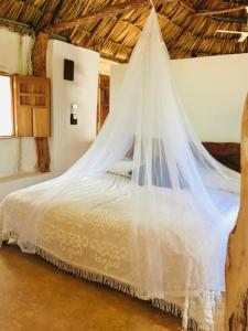 a bedroom with a bed with a mosquito net at Encantadora Villa Maya tradicional en Rancho Agroecologico in Tzucaceb