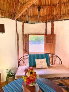 Cette chambre comprend 2 lits et une table fleurie. dans l'établissement Encantadora Villa Maya tradicional en Rancho Agroecologico, à Tzucaceb