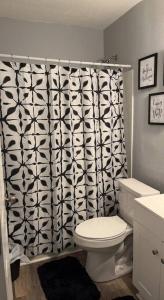 La salle de bains est pourvue de toilettes et d'un rideau de douche noir et blanc. dans l'établissement Lovely Two Bedroom Duplex Near Buckroe Beach, à Hampton