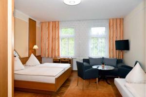 une chambre d'hôtel avec deux lits et un canapé dans l'établissement Panoramahotel Wolfsberg, à Bad Schandau