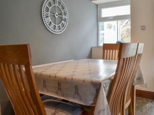 a dining room table with two chairs and a clock on the wall at Rose Cottage - Uk41345 in Cromer