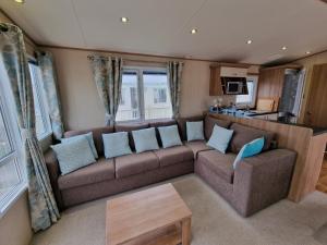 チャペル・セント・レオナルズにあるCosy caravans Meadow viewのリビングルーム(ブラウンソファ、青い枕付)