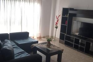 uma sala de estar com um sofá, uma televisão e uma mesa em América 1 em Villa Luzuriaga