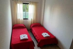 duas camas num pequeno quarto com lençóis vermelhos em América 1 em Villa Luzuriaga