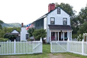 a white picket fence in front of a white house at Upstairs Historic 1 Bedroom 1 Bath Suite with Mini-Kitchen, Porch & River Views in Elkins