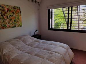 Un dormitorio con una cama grande y una ventana en CASA JARDIN HUERTA PILETA Y PARRILLA San Isidro Bs As en San Isidro