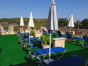 a row of chairs and umbrellas on a lawn at Ilona Apartments Chania in Kato Daratso