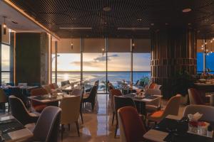 um restaurante com mesas e cadeiras e vista para o oceano em Peninsula Hotel Danang em Da Nang