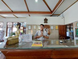 a man standing behind a glass counter with his arms crossed at Puri Merbabu Asri 