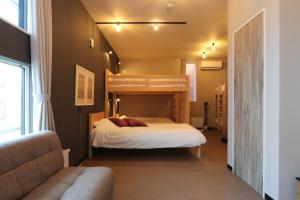 a bedroom with a bunk bed and a couch at UCHI Living Stay ekolu in Sapporo