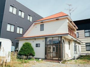 ein weißes Haus mit orangefarbenem Dach in der Unterkunft ゲストハウスVACILANDO in Chitose