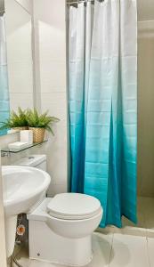 La salle de bains est pourvue de toilettes et d'un rideau de douche bleu. dans l'établissement Azure Urban Resort Residences - Cozy Homes, à Manille