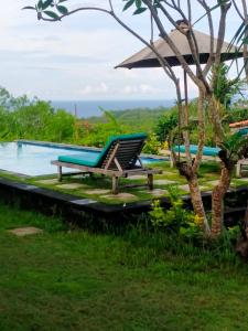 una silla junto a una piscina con el océano en el fondo en Green Bowl Beach Villas, en Uluwatu