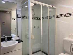 a bathroom with a shower with a sink and a toilet at KozyGuru / Haymarket SYD / Cozy Warm / 1 Bed APT / NHA317-546B in Sydney
