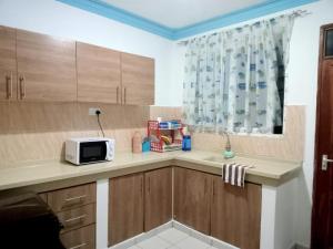 a kitchen with a counter with a microwave and a window at Mtwapa HomeStay 3br Apartments in Mombasa