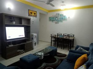 uma sala de estar com um sofá azul e uma televisão em Mtwapa HomeStay 3br Apartments em Mombasa