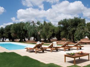 a person sitting in lounge chairs next to a swimming pool at I Mulicchi in Specchia