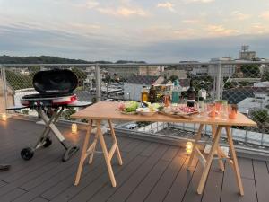 鐮倉的住宿－plat hostel keikyu kamakura wave，阳台配有2张带食物和烧烤的桌子。