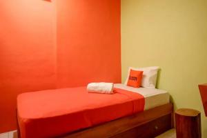 a small bedroom with a bed with orange walls at KoolKost @ Inep Kayu Jebres in Solo