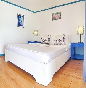 a large white bed in a room with two lamps at Beach Huts El Nido in El Nido