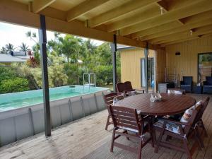 a wooden deck with a table and a swimming pool at Eve and Sandys Holiday Home in Rarotonga