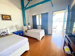 a bedroom with two beds and a room with a window at Beach Huts El Nido in El Nido