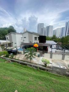 a white house with trees in front of a building at Villa 16pax 3BR with Spa Pool n Pool Table near SPICE ARENA in Bayan Lepas