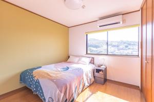 ein kleines Schlafzimmer mit einem Bett und einem Fenster in der Unterkunft LONG VACATION in Shirahama