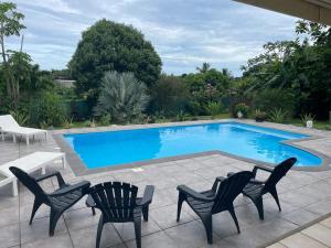 a swimming pool with two chairs and a table at Le Colibris du Lamentin in Lamentin