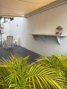a white wall with a table and chairs and plants at Charmante maison avec Jaccuzi et piscine Sunrise beautiful house with Jaccuzi and swimming pool in Lamentin