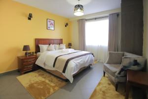 a bedroom with a bed and a chair and a window at Lantern Serviced Apartments in Nairobi