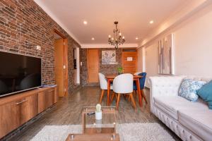 sala de estar con sofá, TV y mesa en Town Center Apartments, en Urubamba