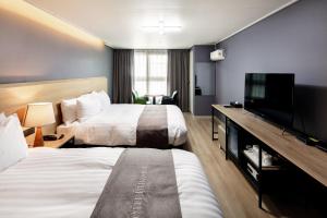 a hotel room with two beds and a flat screen tv at Hotel Bernoui Seoul in Seoul