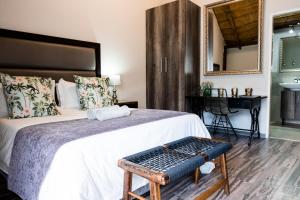 a bedroom with a bed with a bench on it at Villa Gracia Guesthouse in Klerksdorp